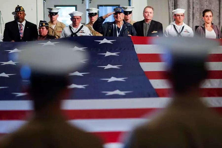 U.S. service members hold the U.S. flag at ceremony honoring the men and women who died while serving in the U.S. Armed Forces.