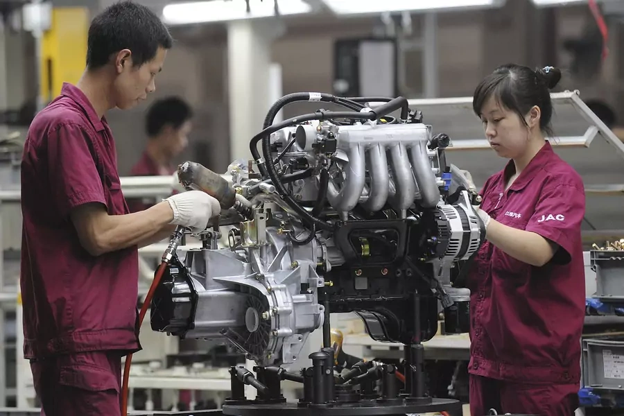 Employees assemble an engine at the production line of an automobile company in Anhui province, China. July 16, 2009.