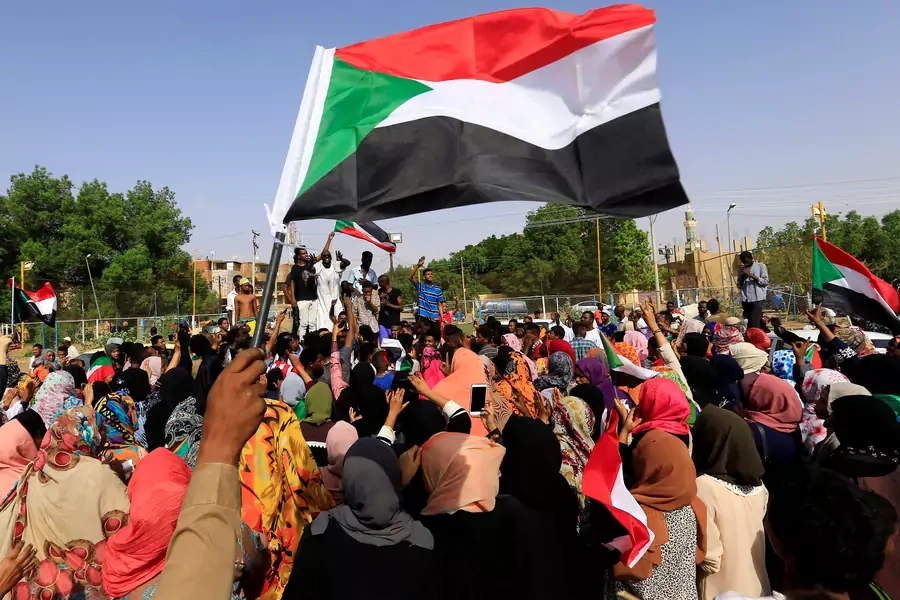 Sudanese demonstrators wave their national flag on the streets of Khartoum in celebration after the country's ruling military council and a coalition of opposition groups reached an agreement to share power during a transition period, July 5, 2019