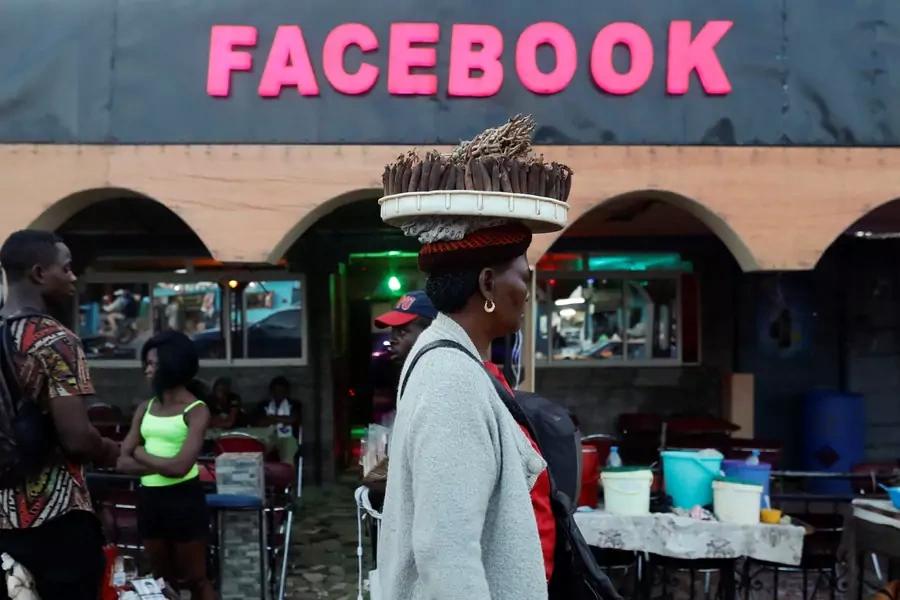 A street vendor walks past a bar called "Facebook" in Yaounde, Cameroon October 2, 2018.