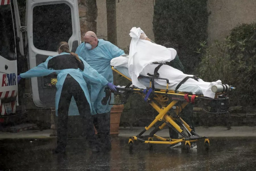 Medics transport a patient through heavy rain into an ambulance at Life Care Center of Kirkland.