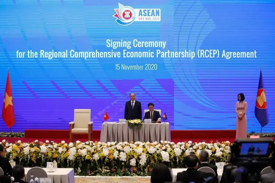 Vietnam's Industry and Trade Minister Tran Tuan Anh (C) signs as Vietnam's Prime Minister Nguyen Xuan Phuc (L) witnesses during the signing ceremony of the Regional Comprehensive Economic Partnership (RCEP) Agreement during the 37th ASEAN Summit in Hanoi,