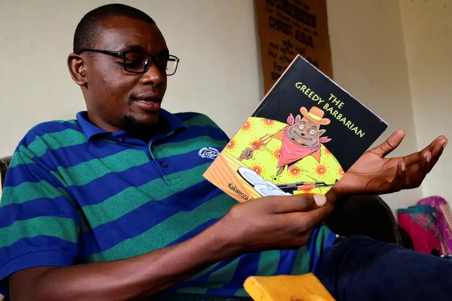 Ugandan author of "Greedy Barbarian" Kakwenza Rukirabashaija reads the book at his home in Iganga district in Eastern Uganda on May 11, 2020.