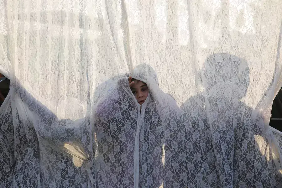 A girl stands behind a curtain that separates between men and women at the gravesite of Rabbi Yisrael Abuhatzeira, a Moroccan-born sage and Kabbalist also known as the Baba Sali, during an annual pilgrimage held on the anniversary of his death in the sout