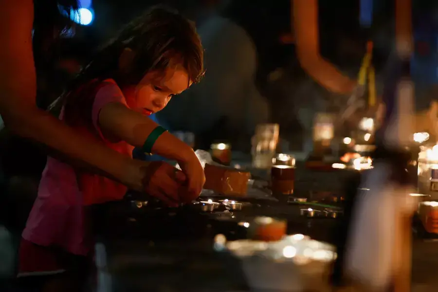 A girl helps to light a candle, as people gather for a candlelit vigil to mark the one-month anniversary of the October 7 deadly attack by Palestinian Islamist group Hamas on Israel, in Tel Aviv, Israel, November 7, 2023.