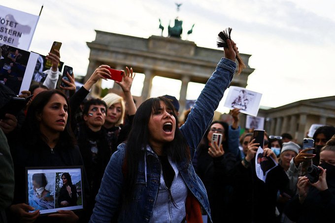 A woman holding hair protests in front of the Brandenburg gate in Berlin.