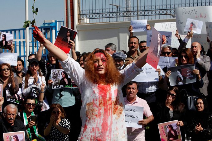 A woman covered in fake blood with both her arms raised protests in Erbil, Iraq.