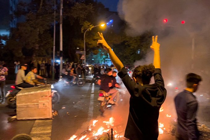 A protester makes a victory sign with both hands raised during a protest in the streets of Tehran.