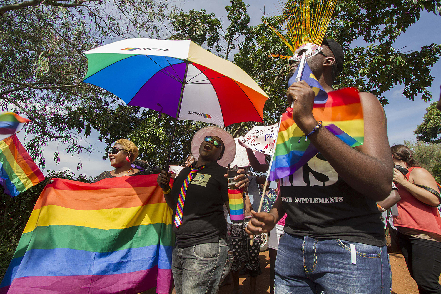 People holding rainbow flags and umbrellas take part in the Gay Pride parade in Entebbe, Uganda.