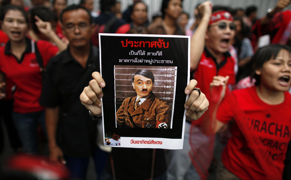 Anti-government red shirt protesters shout slogans holding a  poster with a defaced photo of Thailand’s prime minister Abhisit  Vejjajiva during a protest in central Bangkok