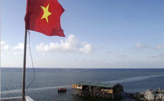 A Vietnamese flag flutters as a motorboat transporting Vietnamese navy personnel passes a construction site of a new pier on Truong Sa islands or Spratly islands