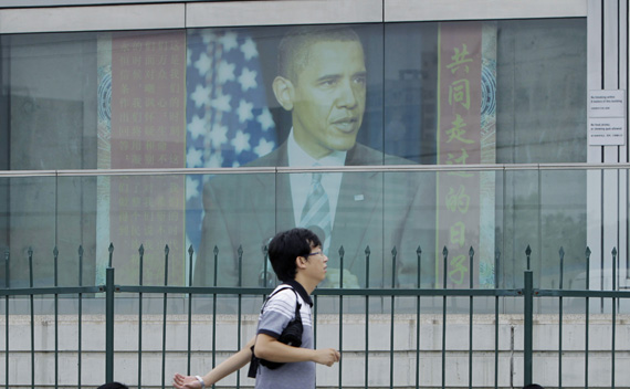 A man walks past a picture of U.S. President Obama outside the U.S. embassy in Beijing