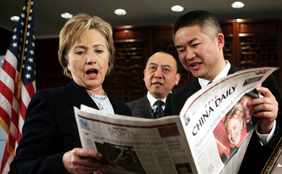 U.S. Secretary of State Hillary Clinton (L) reacts while reading a local English newspaper before conducting a Web chat with Chinese internet users at the U.S. embassy in Beijing February 22, 2009. REUTERS/China Daily