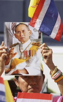 A woman holds a portrait of Thailand’s King Bhumibol Adulyadej on his 83rd birthday in Bangkok