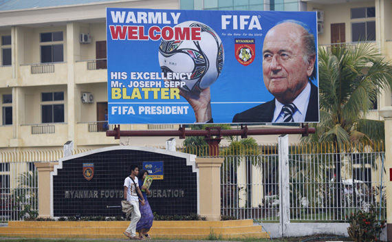 A couple walks below a welcome board for FIFA President Sepp Blatter outside the Myanmar Football Federation in Yangon March 14, 2011.