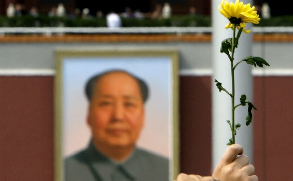 A woman holds a flower aloft in front of the portrait of Chairman Mao Zedong in Beijing’s Tiananmen Square on May 19, 2008.