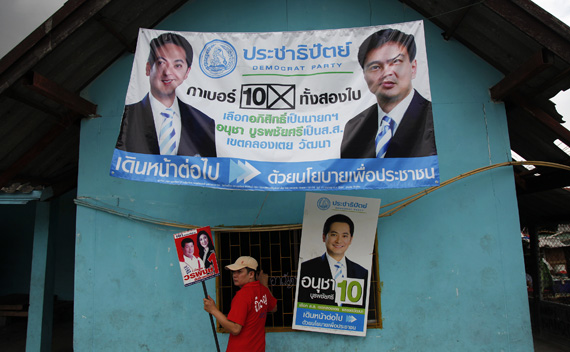 A supporter of Yingluck Shinawatra, sister of toppled premier Thaksin Shinawatra and the prime ministerial candidate for the country’s biggest opposition Pheu Thai Party, holds her poster in front of a building decorated with banners of the Democrat party in Bangkok’s notorious Klong Toey slum June 21, 2011. 