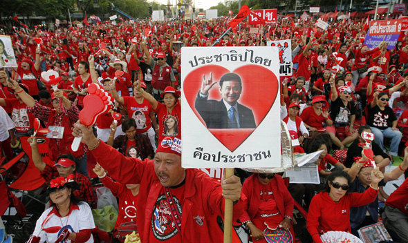 Thailand’s red shirt protester holds pictures of former Prime Minister Thaksin Shinawatra during a rally at the Democracy Monument in Bangkok September 18, 2011.