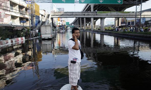 A man stands on sandbags at a flooded intersection in Pathum Thani province, a suburb of Bangkok October 19, 2011. 