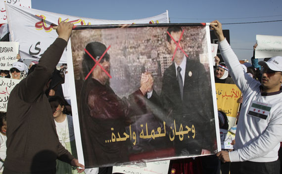 Syrian protesters hold a poster which shows Bashar al-Assad and Muammar Gaddafi during a protest calling for al-Assad to step down in Amman on May 1, 2011.