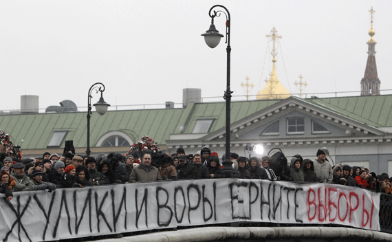 People attend a sanctioned rally on a bridge near Bolotnaya square to protest against violations at the parliamentary elections in Moscow December 10, 2011. Tens of thousands of protesters took to the streets of cities across Russia on Saturday to demand an end to Vladimir Putin’s rule and complain about alleged election fraud in the biggest show of defiance since he took power more than a decade ago. The banner reads 
