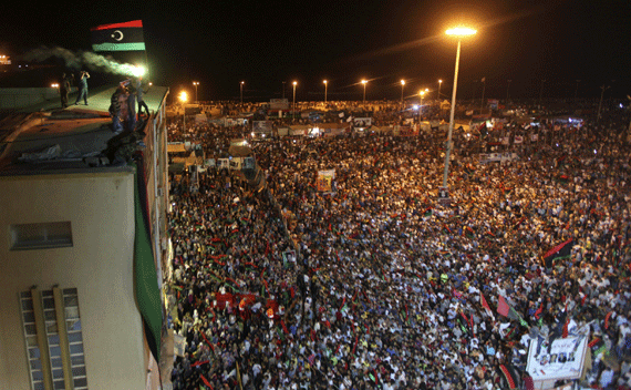 A Kingdom of Libya flag is held aloft a building as people gather near the courthouse in Benghazi August 22, 2011 to celebrate the entry of rebel fighters into Tripoli. Jubilant rebel fighters streamed into the heart of Tripoli as Muammar Gaddafi’s forces collapsed and crowds took to the streets to celebrate, tearing down posters of the Libyan leader. REUTERS/Esam Al-Fetori (LIBYA - Tags: POLITICS CONFLICT)