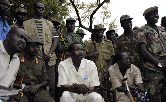 The leader of Uganda’s Lord’s Resistance Army rebels Joseph Kony (seated C), surrounded by his officers, addresses his first news conference in 20 years of rebellion in Nabanga, Sudan, August 1, 2006 where he called on a ceasefire with the government as a prelude to peace talks. BEST QUALITY AVAILABLE REUTERS/Adam Pletts (SUDAN)