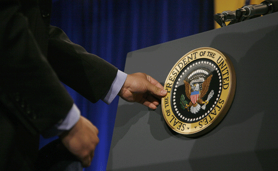 A White House staffer places the Presidential Seal on a lectern before President Obama delivers remarks. 
