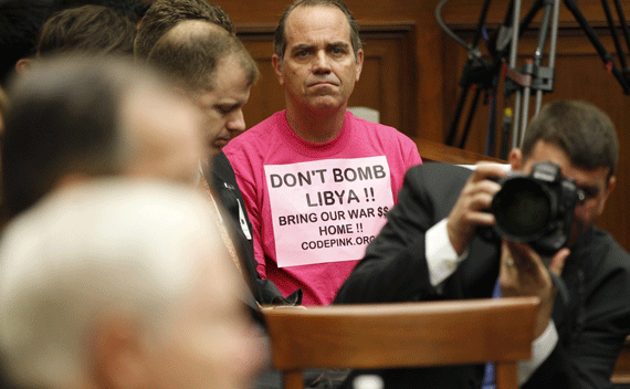 A protester listens as Secretary Gates and Admiral Mullen testify at a House Armed Services Committee hearing on U.S. military operations in Libya on March 31, 2011.