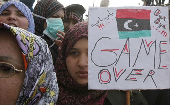 An anti-government protester holds a banner while protesters chant anti-government slogans in Benghazi city