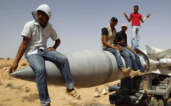 Anti-Gaddafi fighters sit on an SA-5 SAM missile in Burkan air defense military base, which was destroyed by a NATO air strike, September 1, 2011. REUTERS/Goran Tomasevic