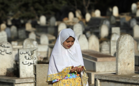 A girl prays near graves on Eid al-Fitr at a cemetery in Ramallah on August 30, 2011 (Mohamad Torokman/Courtesy Reuters).