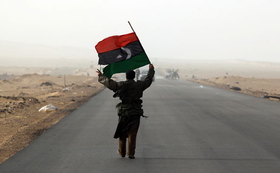 A rebel fighter holds a Kingdom of Libya flag in a battle near Ras Lanuf