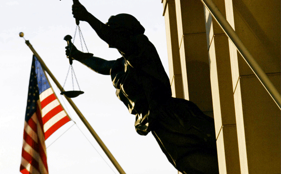 The American flag flies next to a statue of the scales of justice at the U.S. Court House in Alexandria, VA.