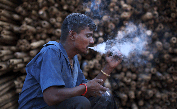 Jagdish, a 32-year-old daily wage labourer, smokes a cigarette while working at a a timber market in Mumbai June 7, 2011. REUTERS/Danish Siddiqui