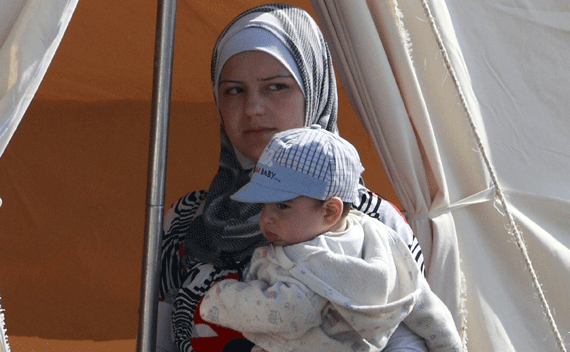 A Syrian refugee holding her child in the Turkish border town of Boynuegin. (Osman Orsal/courtesy Reuters)
