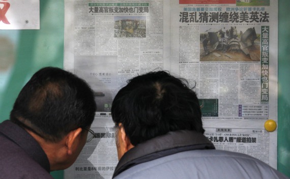 Locals read Chinese newspapers displayed on a public notice board in central Beijing.
