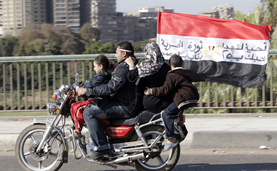 A family of Egyptian pro-democracy supporters ride on a motorcycle carrying an Egyptian flag after Friday prayers near Tahrir Square in Cairo