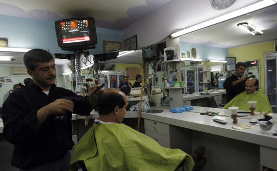 Obama is seen on a television in the background of a barber shop near Ramallah (Mohamad Torokman/Courtesy Reuters)