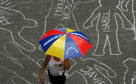 A  woman walks on a street drawn with chalk silhouettes during a protest against violent crimes in Caracas (Courtesy Reuters).