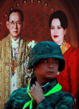 A Thai soldier stands guard near a portrait of Thai King Bhumibol  Adulyadej and Queen Sirikit at a checkpoint in central Bangkok May 21,  2010. 