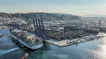 A massive, loaded container ship being tugged from a shipyard.