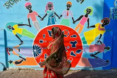 A woman walks past a mural in Kolkata, India, that shows women and girls of various backgrounds holding hands