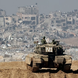 An Israeli tank drives past damaged buildings near the Gaza Strip border in southern Israel on January 19, 2024