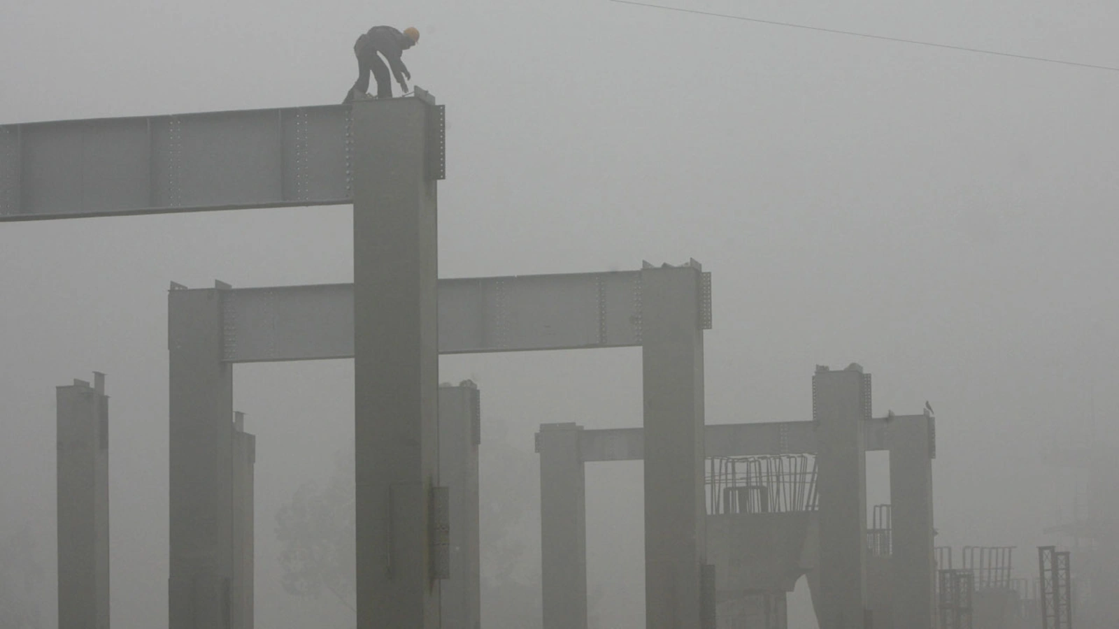 A Delhi Metro Rail Corporation worker works amidst thick fog at a construction site in New Delhi.