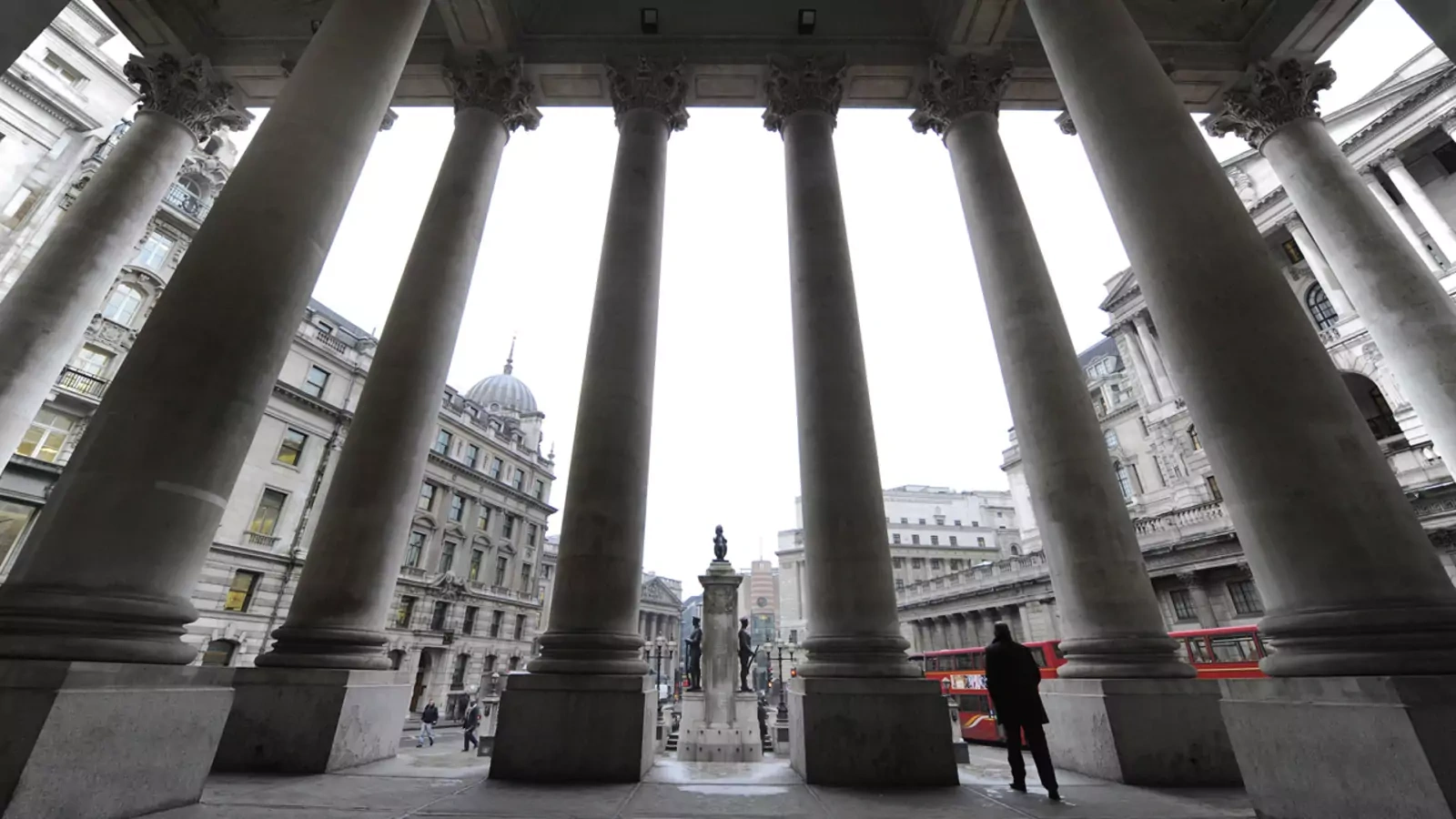 People walk through the Royal Exchange in front of the Bank of England in central London.
