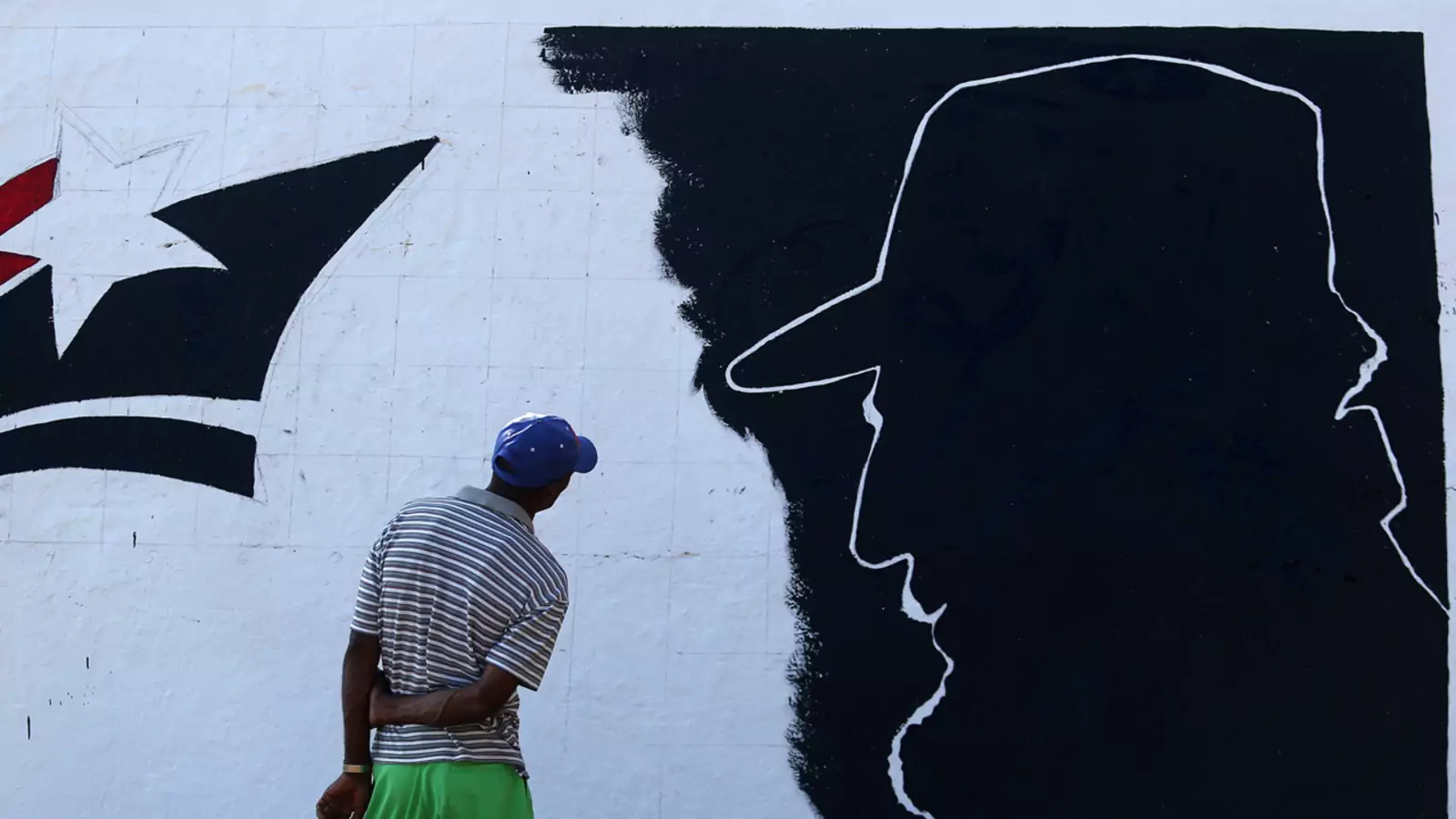 A man looks at a mural representing Cuba's late President Fidel Castro located along Cuba's southern coast.