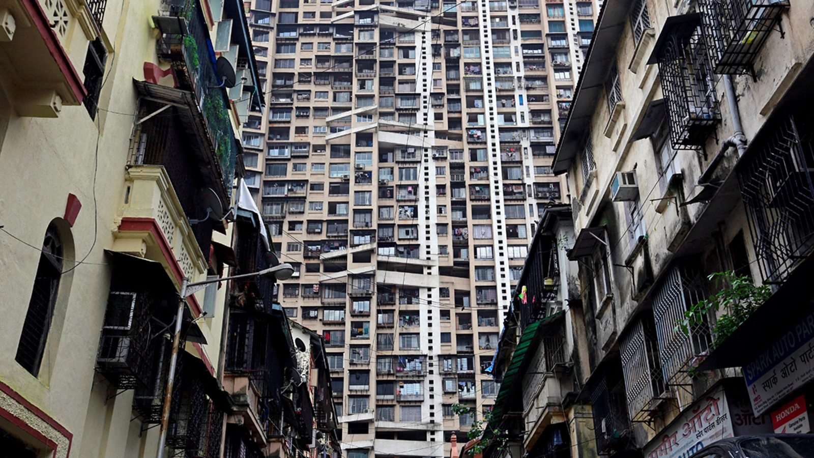 A residential tower rises behind older residential buildings in Mumbai, India, in 2017.