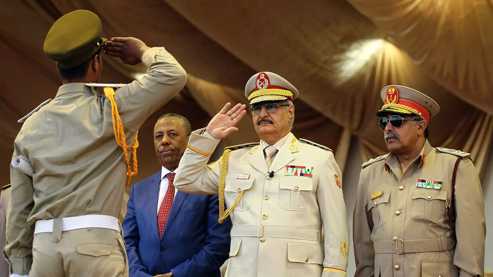 Khalifa Haftar (C), leader of the Libyan National Army, salutes next to his Chief Of Staff Abdelrazak al-Nadhuri (R) and Libyan former prime minister Abdullah al-Thani