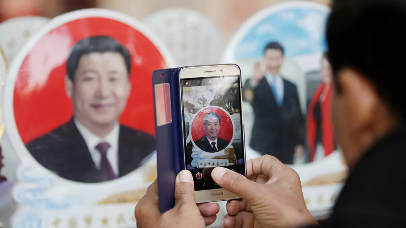 During the Nineteenth Party Congress of the Chinese Communist Party in Beijing in 2017, a tourist photographs a souvenir plate featuring Chinese President Xi Jinping in a shop near Tiananmen Square.